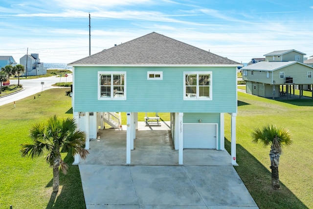 view of front of home featuring a garage, a carport, roof with shingles, and a front yard