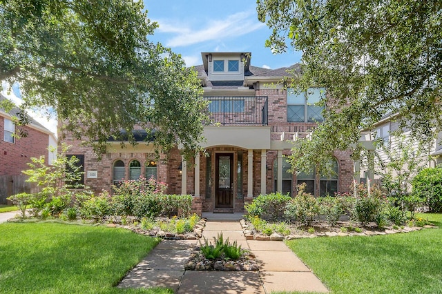 view of front of house with a front yard, brick siding, and a balcony