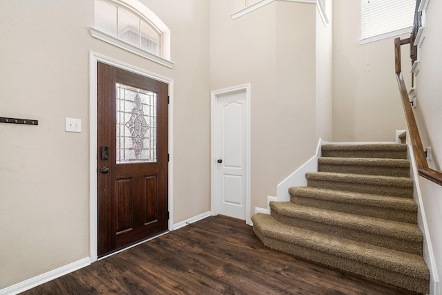 entryway with stairs, dark wood finished floors, and baseboards