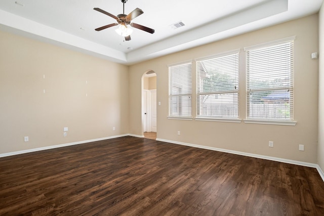 unfurnished room featuring baseboards, visible vents, arched walkways, ceiling fan, and dark wood-style flooring