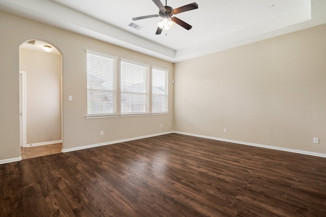 empty room featuring dark wood-type flooring, arched walkways, visible vents, and ceiling fan