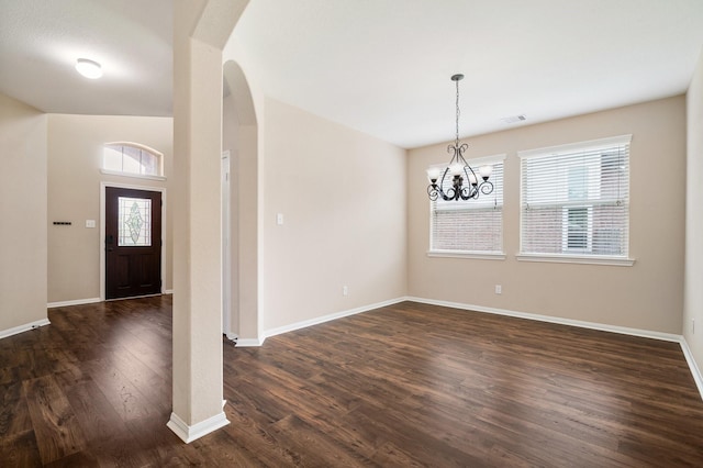 foyer entrance with arched walkways, dark wood-style flooring, visible vents, and baseboards