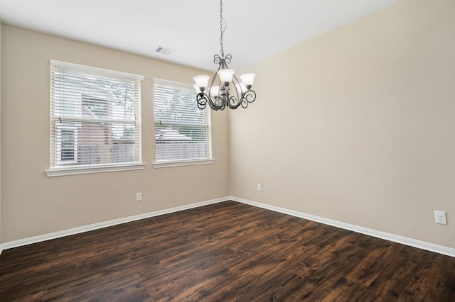 empty room featuring dark wood-type flooring, a chandelier, visible vents, and baseboards