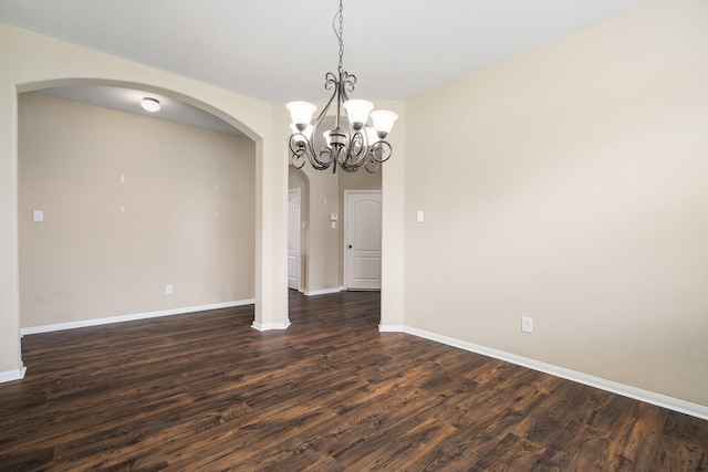 unfurnished dining area with a chandelier, arched walkways, dark wood finished floors, and baseboards