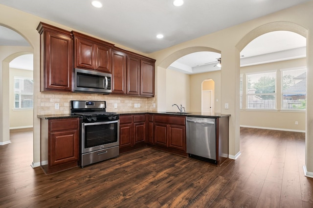 kitchen featuring tasteful backsplash, appliances with stainless steel finishes, dark wood-type flooring, and a sink