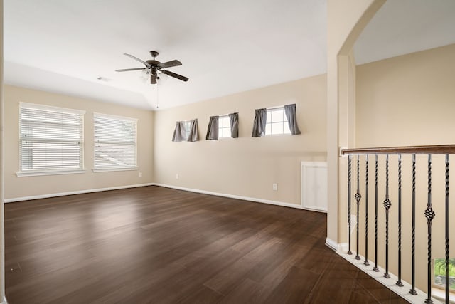 unfurnished room featuring dark wood-style floors, plenty of natural light, baseboards, and ceiling fan