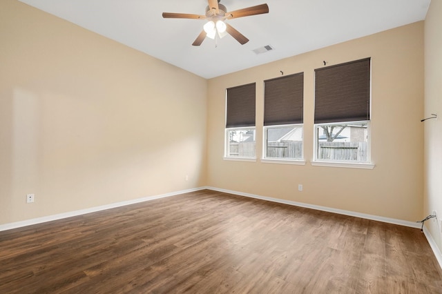 spare room with baseboards, visible vents, ceiling fan, and wood finished floors