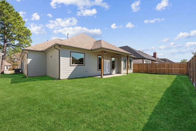 back of house featuring a yard, a shingled roof, a patio, and a fenced backyard