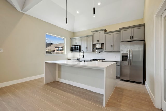 kitchen featuring appliances with stainless steel finishes, light countertops, a sink, and gray cabinetry