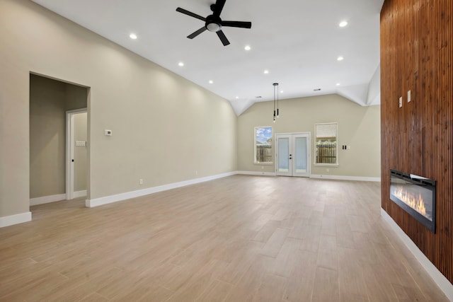 unfurnished living room featuring a large fireplace, vaulted ceiling, light wood-style flooring, and a ceiling fan