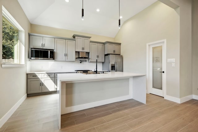 kitchen featuring stainless steel appliances, range hood, a center island with sink, and gray cabinetry