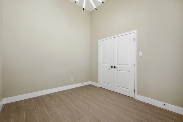 unfurnished room with wood finish floors, a towering ceiling, and baseboards