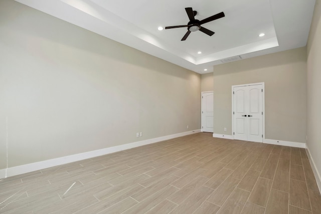 unfurnished room featuring recessed lighting, a raised ceiling, visible vents, light wood-style floors, and baseboards