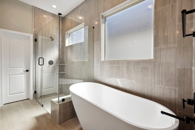 bathroom featuring a freestanding bath, a stall shower, and tile walls