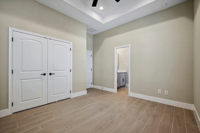 unfurnished bedroom with visible vents, baseboards, ensuite bath, wood tiled floor, and a closet