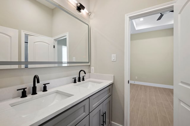 bathroom featuring double vanity, wood finished floors, a sink, and baseboards