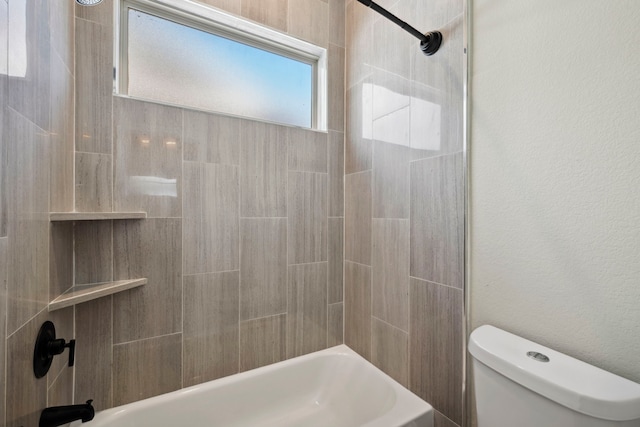 bathroom featuring toilet, shower / washtub combination, and a textured wall