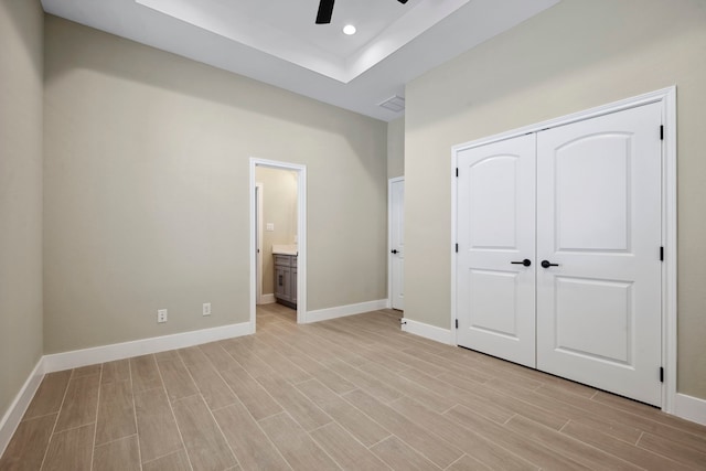 unfurnished bedroom with recessed lighting, a closet, light wood-style floors, connected bathroom, and baseboards