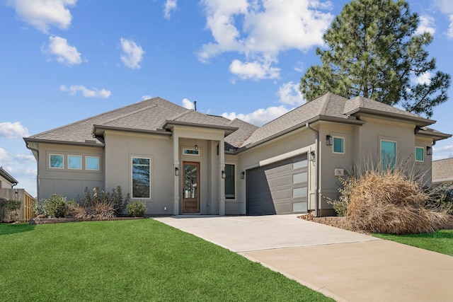 prairie-style house featuring a garage, driveway, a front yard, and stucco siding