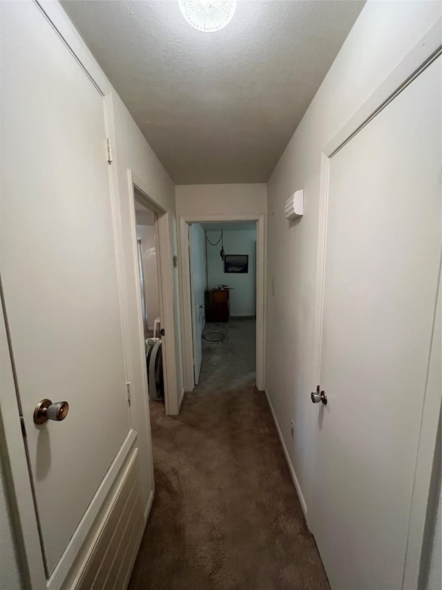 hall featuring a textured ceiling, carpet flooring, and baseboards