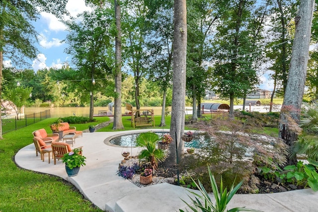 view of property's community featuring a patio area, a lawn, and fence