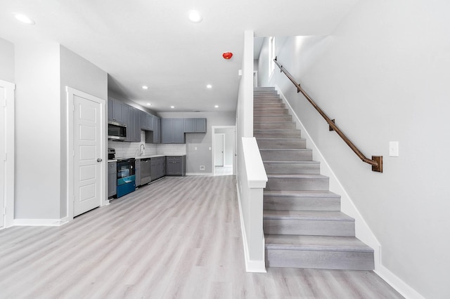 staircase featuring baseboards, wood finished floors, and recessed lighting