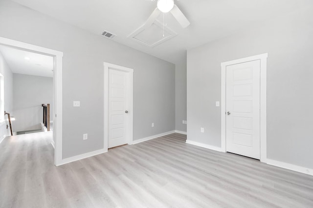 unfurnished bedroom featuring a ceiling fan, baseboards, visible vents, light wood-type flooring, and attic access