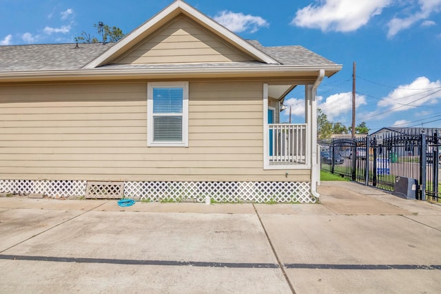 view of property exterior with a shingled roof and fence