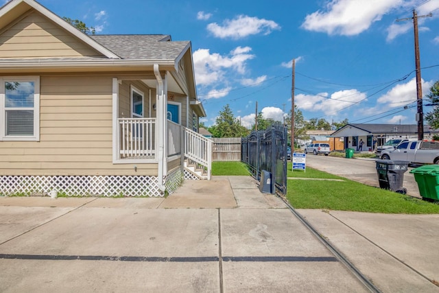 view of property exterior featuring a shingled roof, a yard, and fence