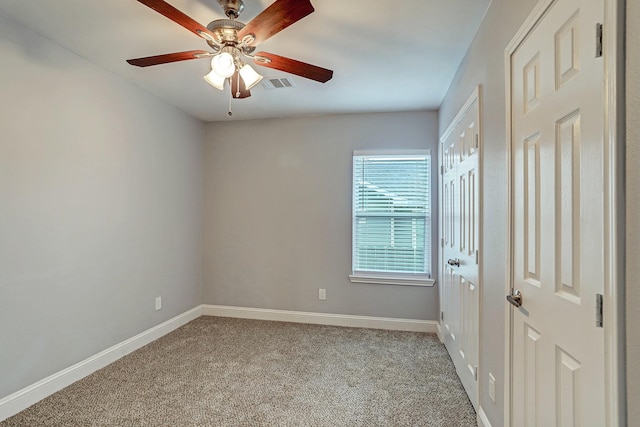 carpeted spare room featuring visible vents, ceiling fan, and baseboards