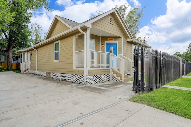 view of front facade featuring driveway, covered porch, and fence