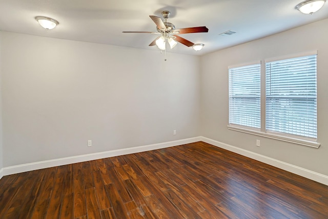 unfurnished room with baseboards, visible vents, ceiling fan, and dark wood-type flooring