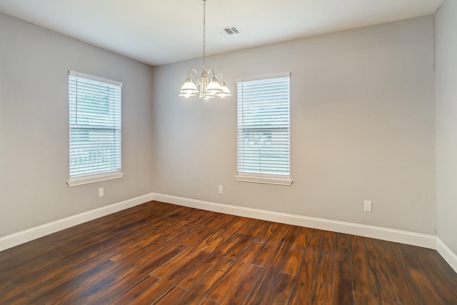 spare room featuring an inviting chandelier, visible vents, baseboards, and dark wood-type flooring