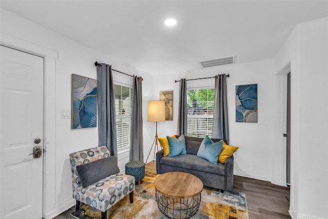 living area with baseboards, visible vents, and wood finished floors