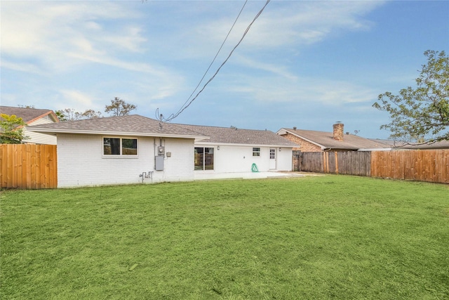 back of house with a patio area, a fenced backyard, a lawn, and brick siding