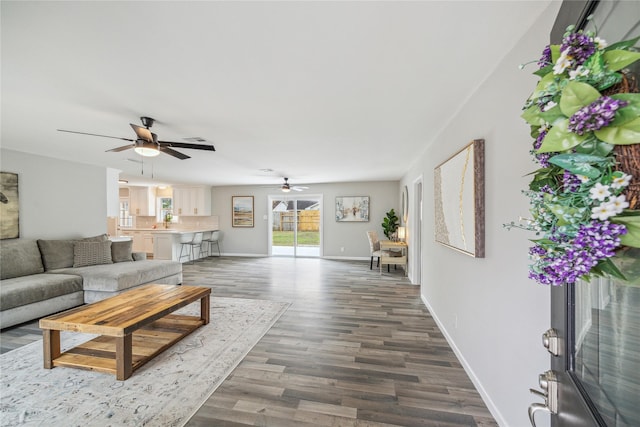 living room featuring dark wood-style floors, ceiling fan, and baseboards