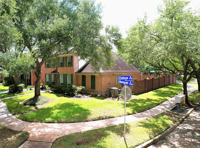 view of front of home with fence, a front lawn, and brick siding