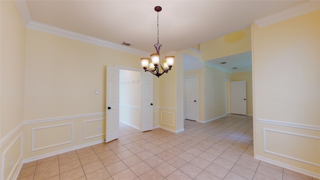 spare room featuring light tile patterned floors, visible vents, wainscoting, crown molding, and a decorative wall