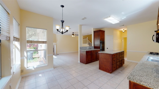 kitchen featuring light tile patterned floors, oven, a sink, light stone countertops, and decorative light fixtures