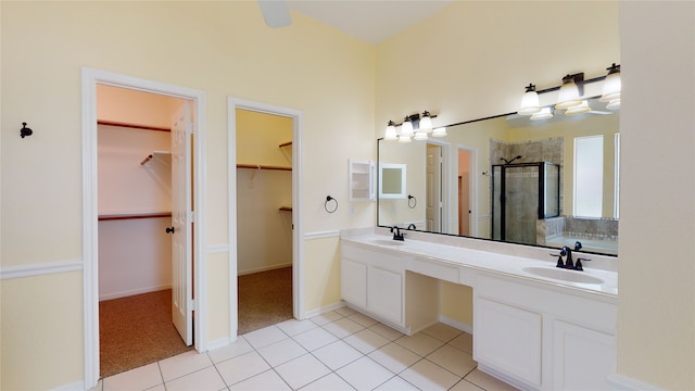 full bathroom with a stall shower, a sink, a spacious closet, and tile patterned floors