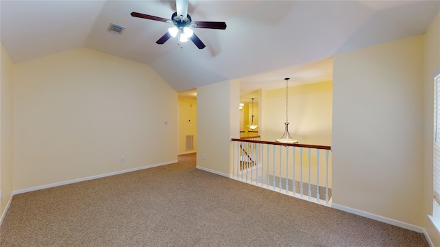 carpeted empty room with visible vents, baseboards, and vaulted ceiling