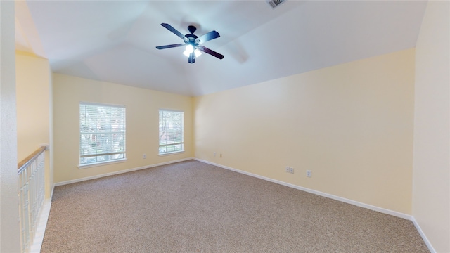 empty room featuring carpet floors, lofted ceiling, visible vents, and baseboards