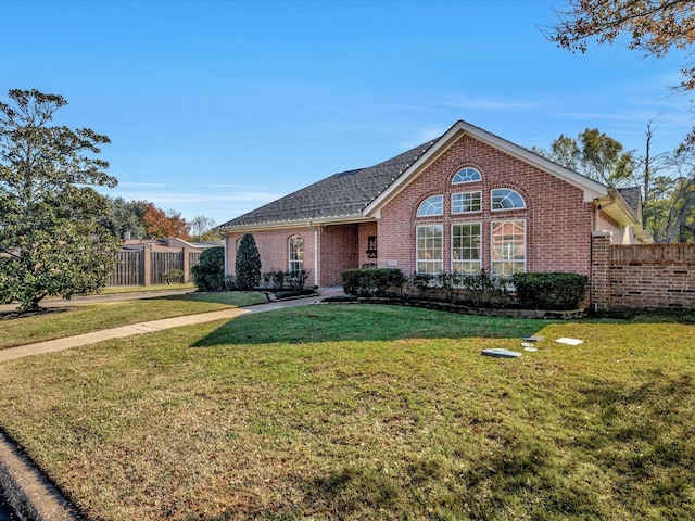 view of front of house featuring a front yard, fence, and brick siding