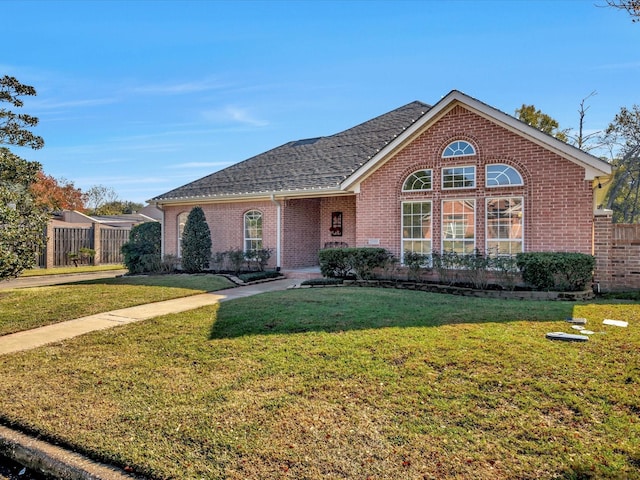 view of front of property featuring brick siding, a front lawn, and a shingled roof