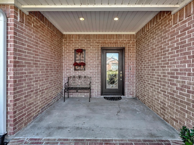 entrance to property featuring brick siding and a patio area