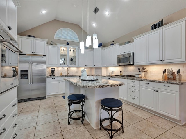 kitchen featuring light tile patterned floors, stainless steel appliances, a breakfast bar area, and white cabinetry