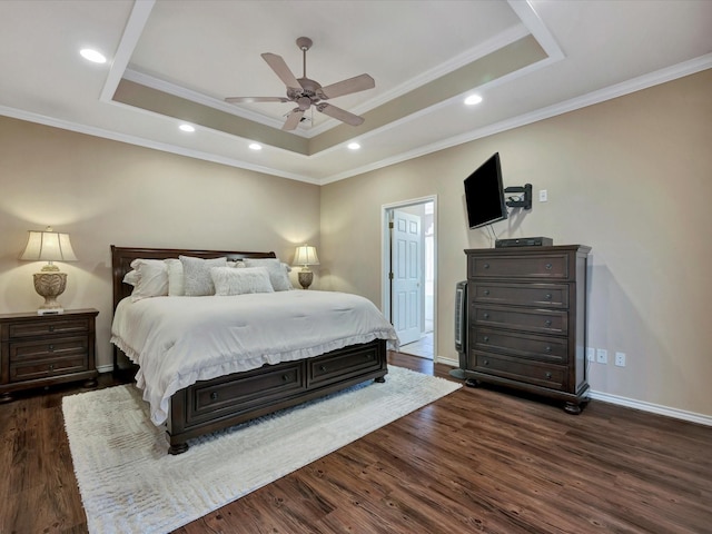 bedroom with a tray ceiling, dark wood-style flooring, and baseboards