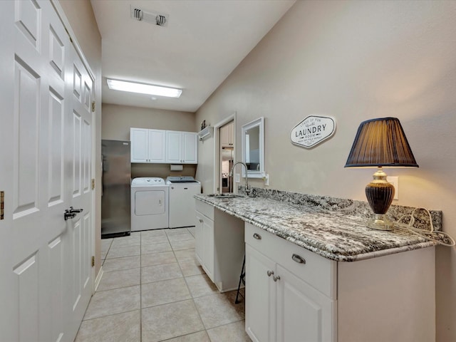 kitchen featuring washer and clothes dryer, visible vents, white cabinets, a sink, and light tile patterned flooring