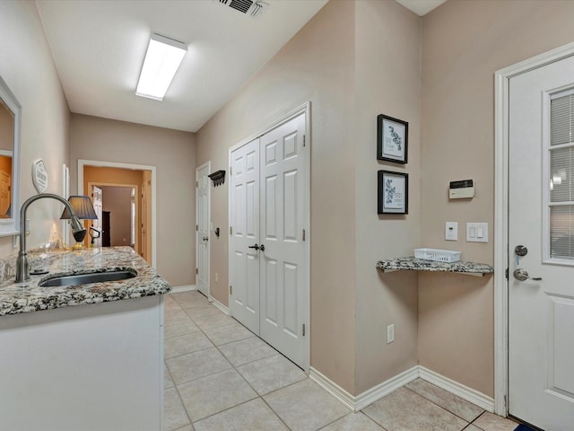 doorway to outside featuring light tile patterned flooring, a sink, visible vents, and baseboards