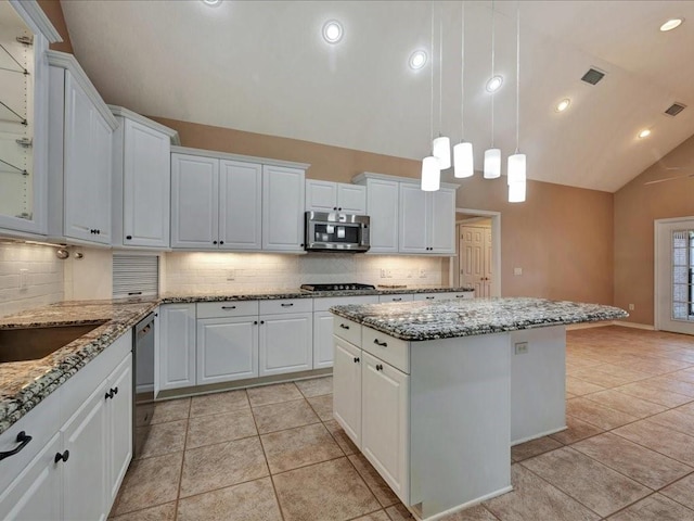 2601 Woodstock Dr, Lufkin, TX 75904 - kitchen with appliances with stainless steel finishes, vaulted ceiling, a kitchen island, light tile patterned flooring, and backsplash
